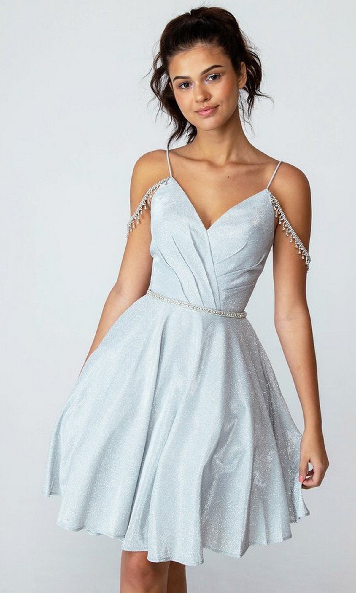 A woman poses against a plain background in the Eureka 9722 Short Prom Dress, featuring an ice blue fit-and-flare silhouette with thin straps, a flared skirt, and sparkling off-the-shoulder jeweled chains for an elegant touch.